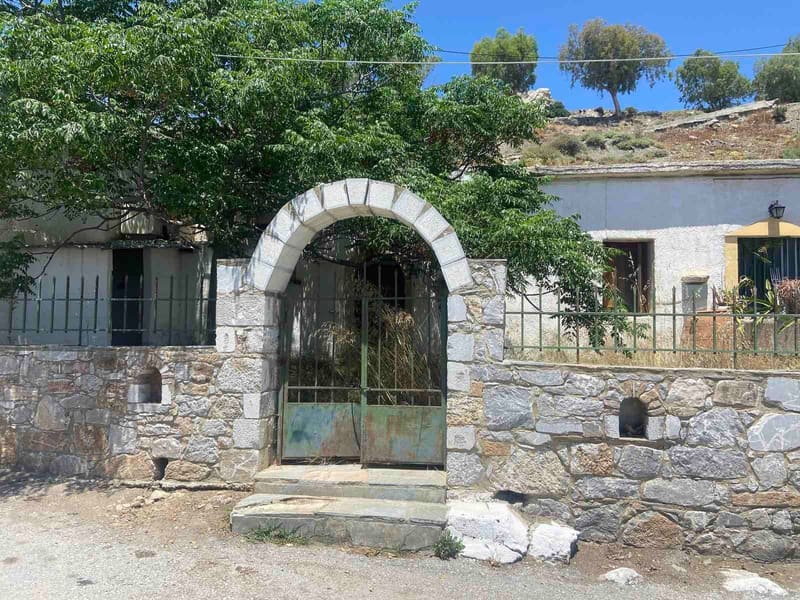 Η πέτρινη μάντρα και η καμαρωτή αυλόπορτα από τον δρόμο