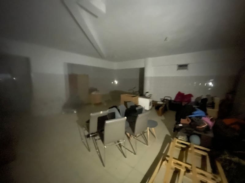 Άλλη άποψη του υπογείου, με καρέκλες, τραπέζια και αντικείμενα αποθηκευμένα, με χαμηλό φωτισμό
